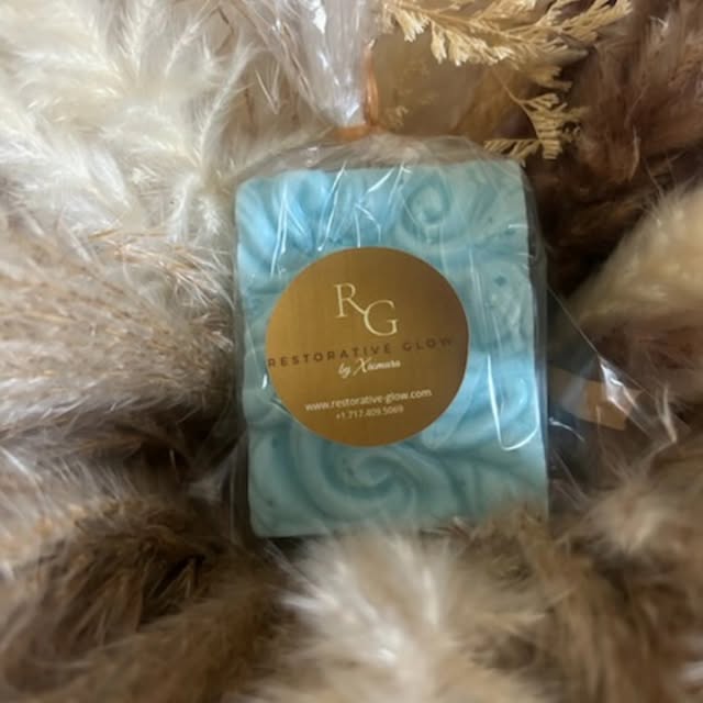 Blue swirl soap bar wrapped with a gold Restorative Glow label